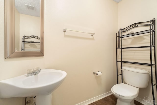 bathroom with sink, a textured ceiling, and toilet