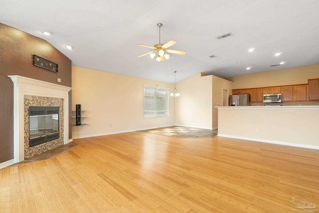 unfurnished living room with a high end fireplace, vaulted ceiling, and light hardwood / wood-style flooring