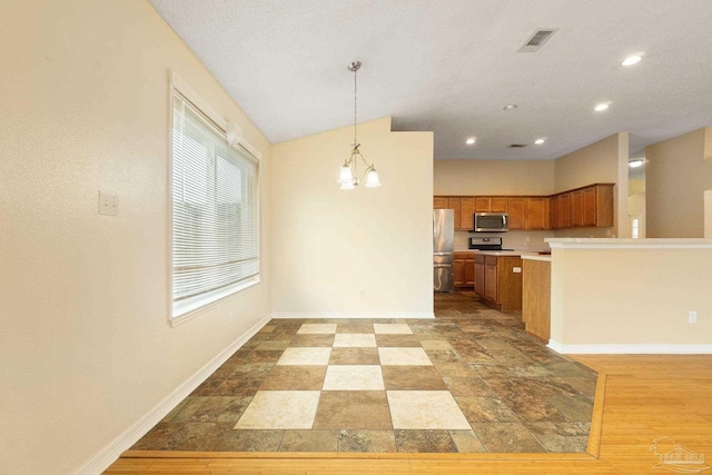 kitchen with appliances with stainless steel finishes, a textured ceiling, an inviting chandelier, and decorative light fixtures