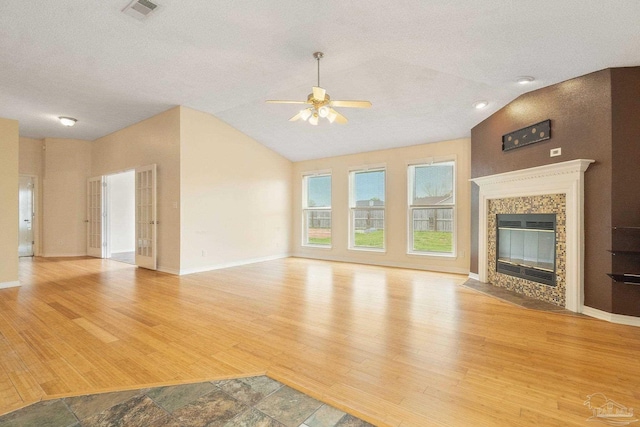 unfurnished living room featuring lofted ceiling, light hardwood / wood-style floors, a premium fireplace, and ceiling fan