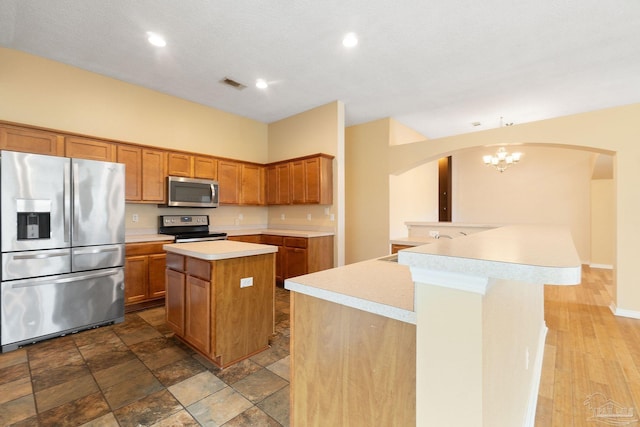 kitchen featuring appliances with stainless steel finishes, a center island, a textured ceiling, and kitchen peninsula