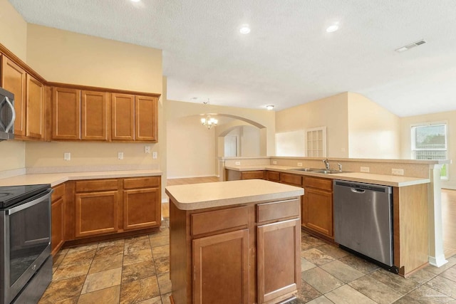 kitchen with sink, an inviting chandelier, stainless steel appliances, a center island, and a textured ceiling