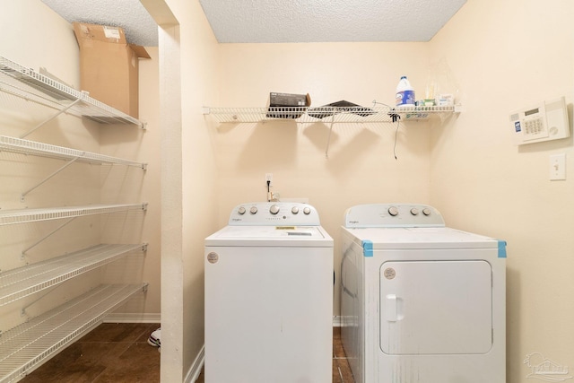 laundry room featuring dark tile patterned flooring, washer and clothes dryer, and a textured ceiling