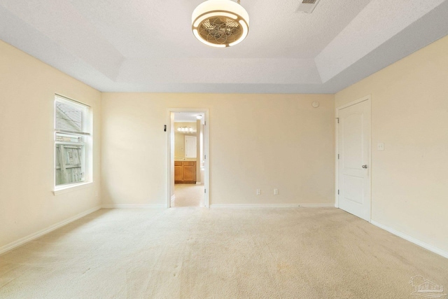 carpeted spare room with a tray ceiling and a textured ceiling