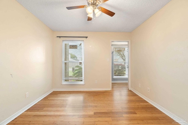 spare room featuring a textured ceiling, light hardwood / wood-style flooring, and a healthy amount of sunlight