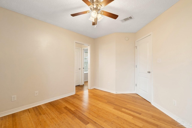 empty room with ceiling fan, light hardwood / wood-style floors, and a textured ceiling