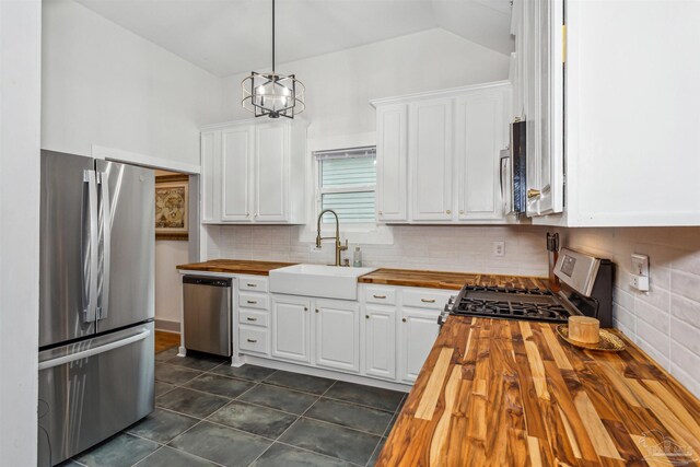 kitchen with white cabinetry, backsplash, appliances with stainless steel finishes, butcher block countertops, and sink