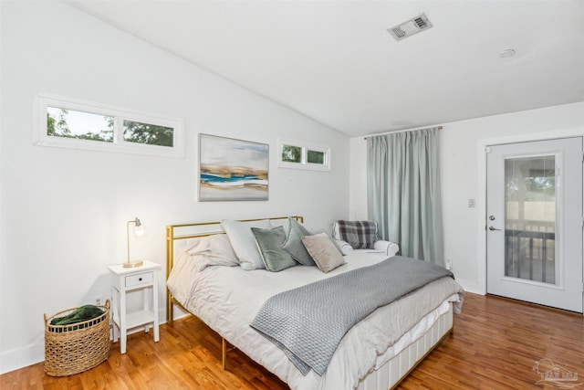 bedroom with lofted ceiling, access to outside, and hardwood / wood-style floors