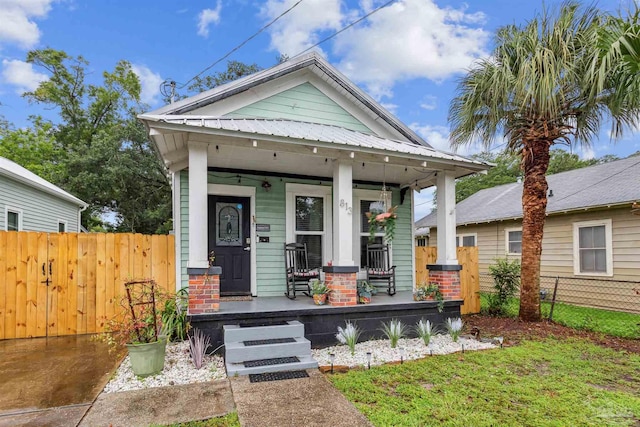 view of front facade featuring a porch, fence, and metal roof