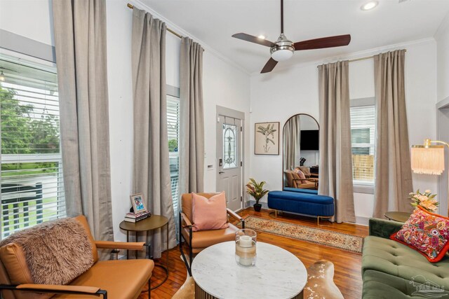 living room featuring hardwood / wood-style flooring, ornamental molding, and ceiling fan