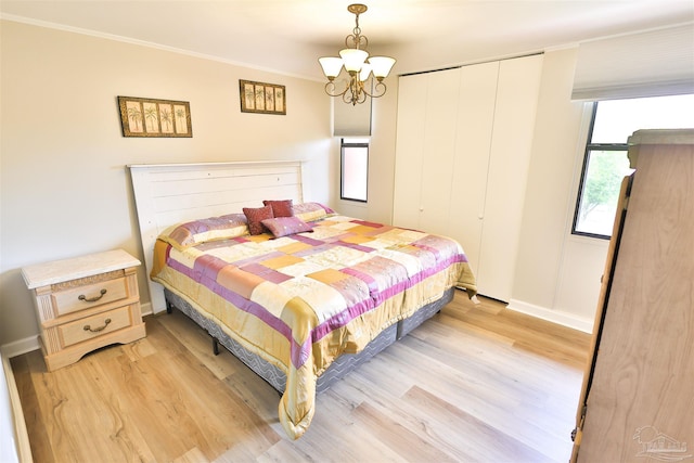 bedroom featuring a closet, crown molding, a notable chandelier, and light hardwood / wood-style flooring