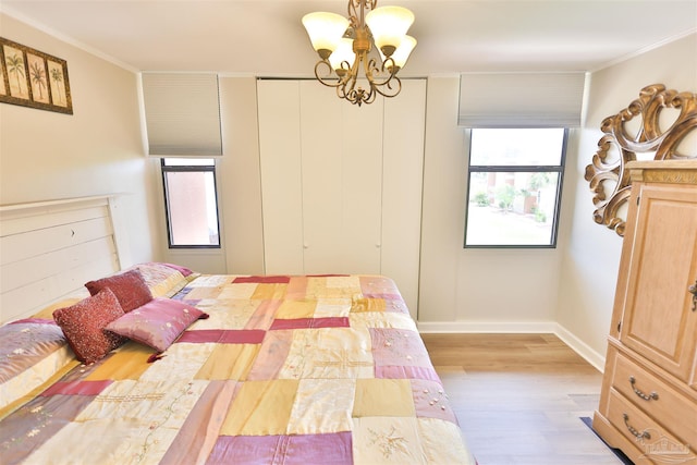 bedroom featuring light hardwood / wood-style floors, crown molding, and an inviting chandelier