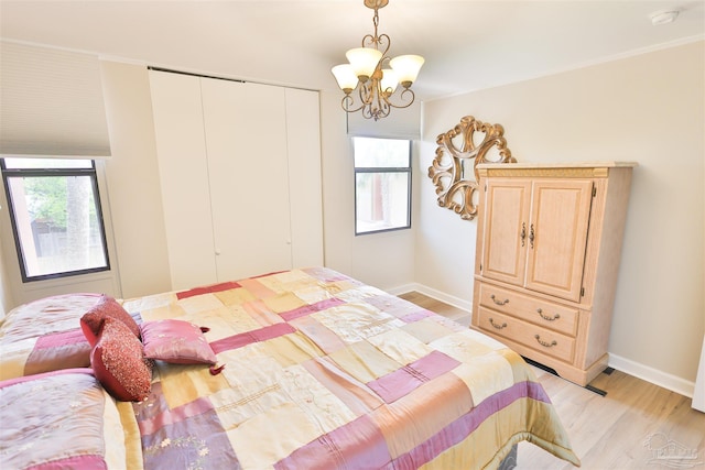 bedroom featuring light wood-type flooring, a chandelier, multiple windows, and a closet