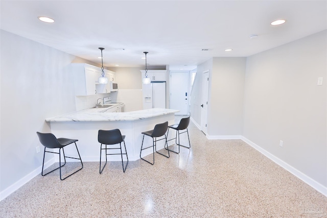 kitchen featuring pendant lighting, white cabinets, white appliances, a kitchen bar, and kitchen peninsula