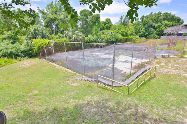 view of tennis court featuring a lawn