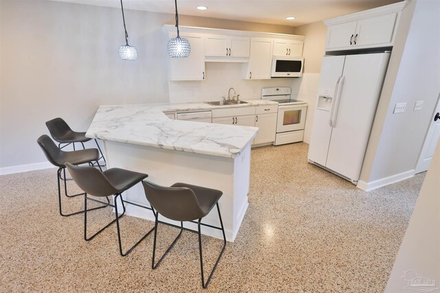 kitchen featuring white appliances, white cabinets, a breakfast bar, sink, and pendant lighting