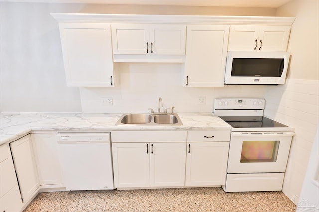 kitchen with white appliances, white cabinetry, sink, and light stone counters