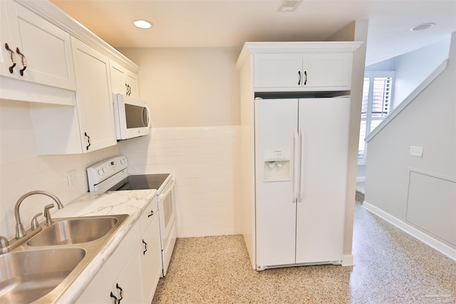 kitchen featuring white appliances, white cabinetry, sink, and tile walls