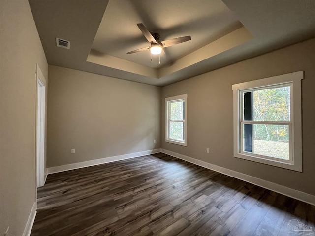 spare room with a raised ceiling, ceiling fan, and dark wood-type flooring