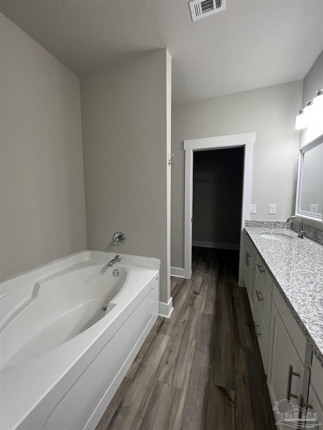 bathroom featuring a textured ceiling, vanity, hardwood / wood-style flooring, and a bathing tub