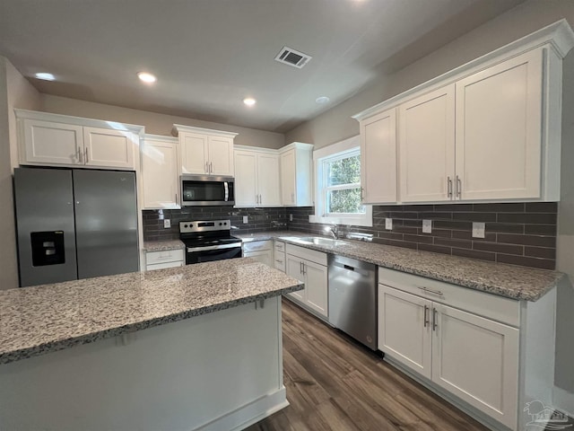 kitchen with white cabinets, sink, light stone countertops, appliances with stainless steel finishes, and dark hardwood / wood-style flooring