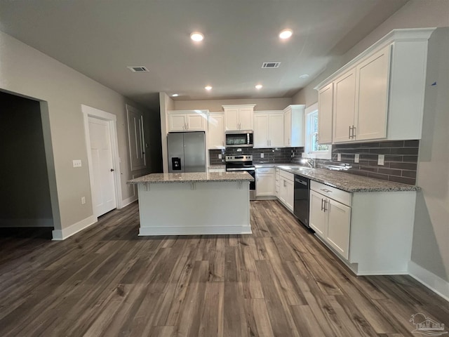 kitchen featuring a center island, white cabinets, sink, light stone counters, and stainless steel appliances