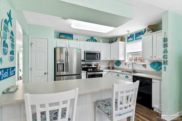 kitchen with sink, stainless steel appliances, dark hardwood / wood-style flooring, a kitchen bar, and white cabinets