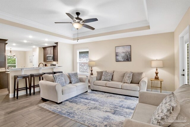 2956 N 17th Ave, Milton, FL 32583 - living area with a tray ceiling, light wood-style floors, ornamental molding, a ceiling fan, and plenty of natural light