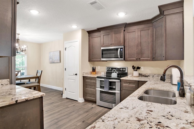 2956 N 17th Ave, Milton, FL 32583 - kitchen featuring stainless steel appliances, a sink, wood finished floors, dark brown cabinets, and light stone countertops