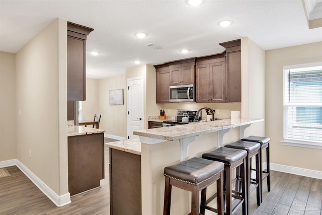 2956 N 17th Ave, Milton, FL 32583 - kitchen featuring stainless steel microwave, electric range, baseboards, wood finished floors, and a peninsula