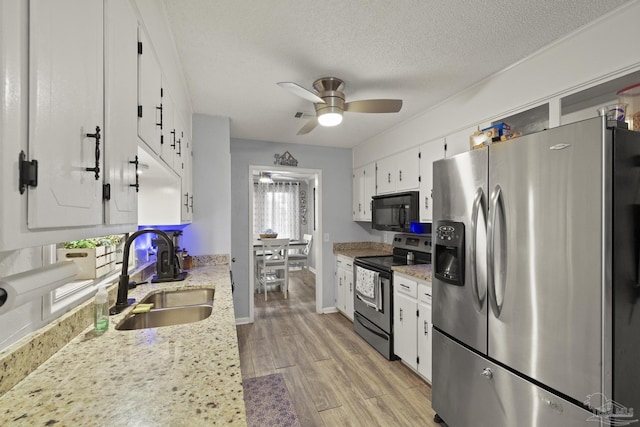 kitchen featuring white cabinetry, appliances with stainless steel finishes, light stone countertops, and sink