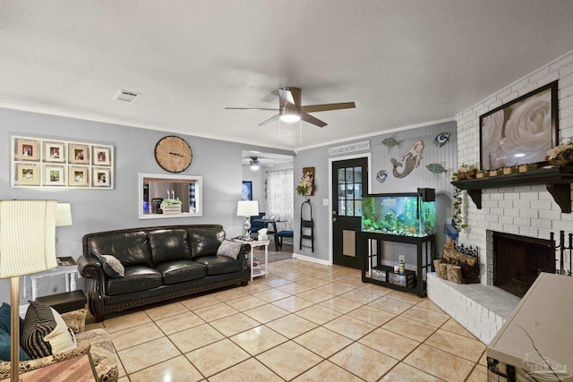 living room featuring a brick fireplace, ornamental molding, ceiling fan, and light tile patterned flooring