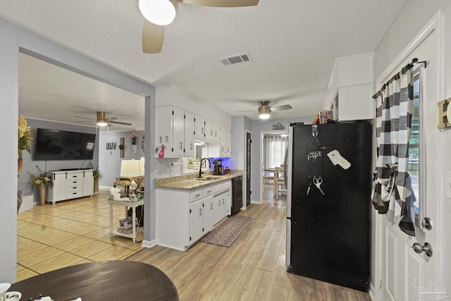 kitchen featuring sink, light hardwood / wood-style flooring, stainless steel fridge, black dishwasher, and white cabinets