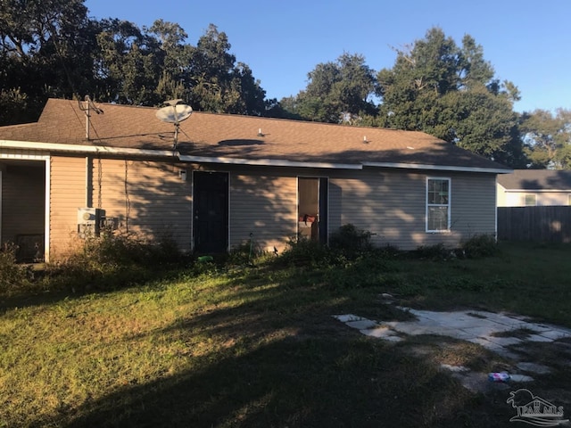 back of house featuring a lawn and fence