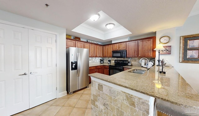 931 W Beach Blvd Unit 501, Gulf Shores, AL 36542 - kitchen with black appliances, a sink, a peninsula, a tray ceiling, and light stone countertops