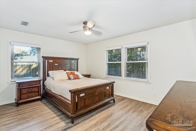 bedroom featuring ceiling fan, multiple windows, and light hardwood / wood-style flooring