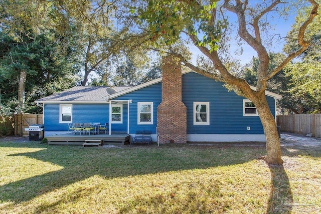 back of property featuring a wooden deck and a yard