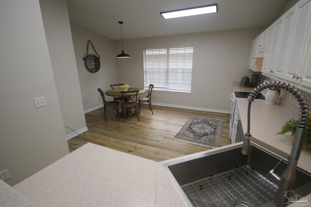 kitchen featuring white cabinets, light wood-type flooring, and baseboards