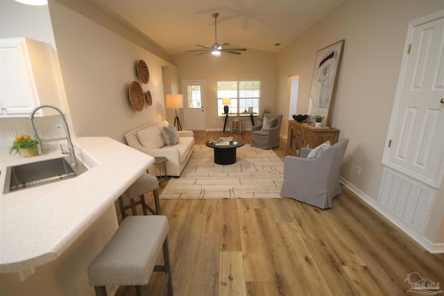 living room featuring baseboards, light wood-style flooring, visible vents, lofted ceiling, and ceiling fan