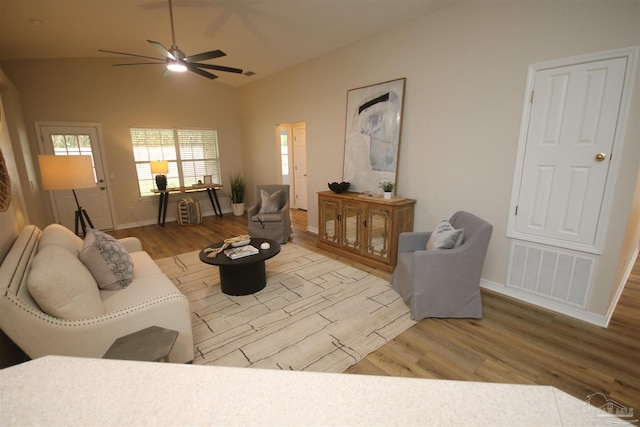 living area with a ceiling fan, vaulted ceiling, visible vents, wood finished floors, and baseboards