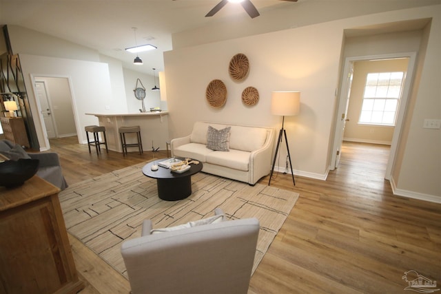 living room featuring wood finished floors, baseboards, a ceiling fan, and lofted ceiling