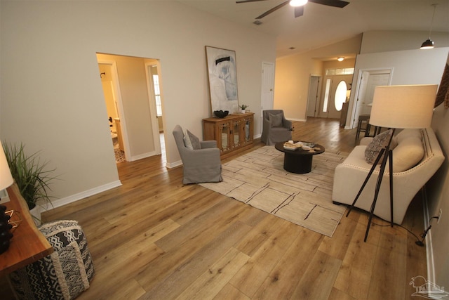 living area featuring wood finished floors, baseboards, a ceiling fan, and lofted ceiling