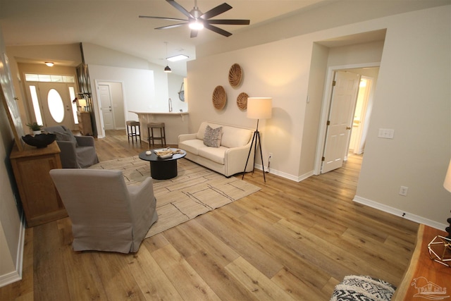 living area with baseboards, a ceiling fan, wood finished floors, and lofted ceiling