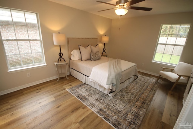 bedroom featuring baseboards, light wood-type flooring, and a ceiling fan