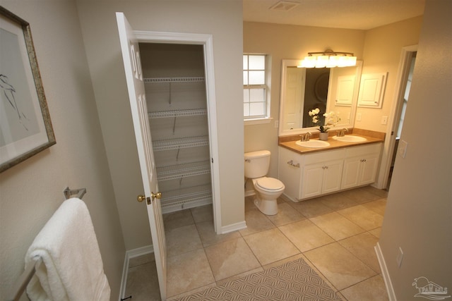 bathroom featuring toilet, tile patterned floors, double vanity, and a sink