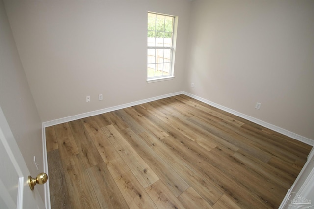 spare room featuring baseboards and wood finished floors