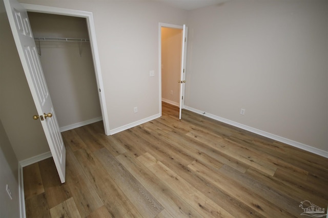 unfurnished bedroom with a closet, baseboards, and wood finished floors