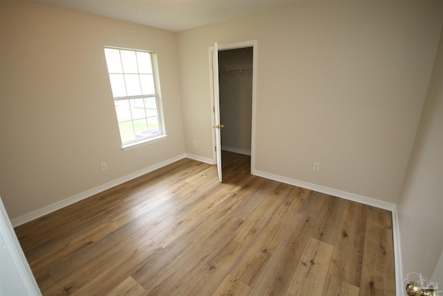 unfurnished bedroom with a closet, light wood finished floors, and baseboards