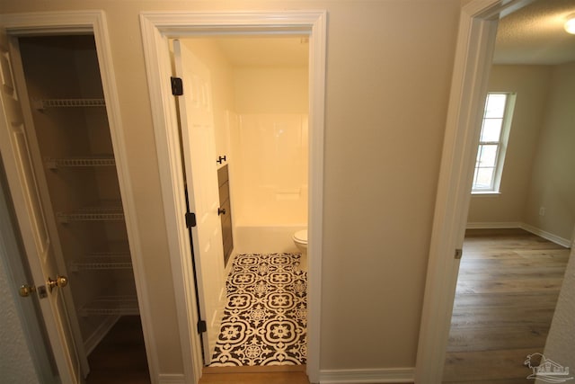 hall with baseboards and wood finished floors