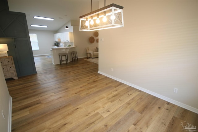 dining area featuring baseboards, light wood-type flooring, and lofted ceiling